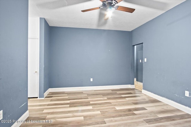 empty room with ceiling fan, baseboards, and wood finished floors