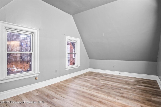 bonus room with lofted ceiling, baseboards, and wood finished floors