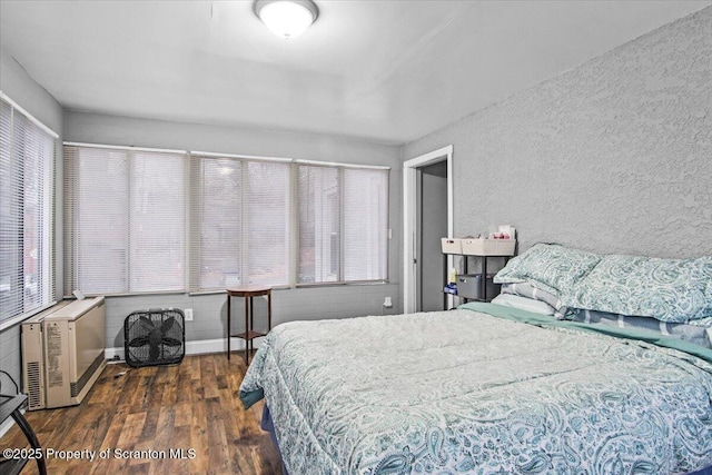 bedroom featuring a textured wall, heating unit, and wood finished floors