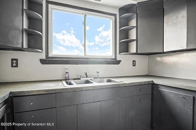 kitchen featuring open shelves, gray cabinets, a sink, and light countertops