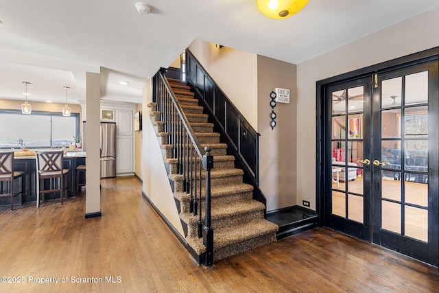 entryway with french doors, baseboards, wood finished floors, and stairway