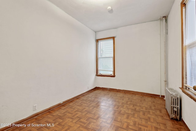 empty room featuring radiator and baseboards