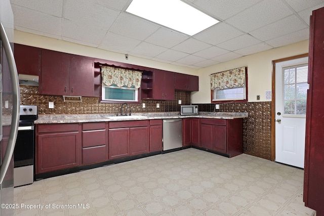 kitchen featuring stainless steel appliances, a sink, light flooring, reddish brown cabinets, and open shelves