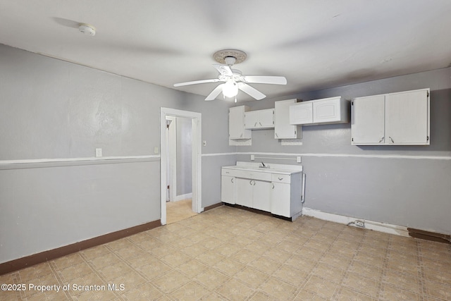 kitchen with white cabinetry, ceiling fan, baseboards, and light countertops