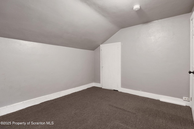 bonus room featuring lofted ceiling, dark colored carpet, and baseboards