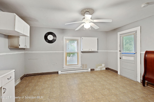 empty room with baseboard heating, ceiling fan, baseboards, and light flooring