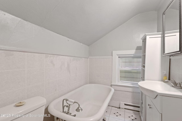 bathroom with lofted ceiling, tile walls, a baseboard heating unit, a soaking tub, and vanity