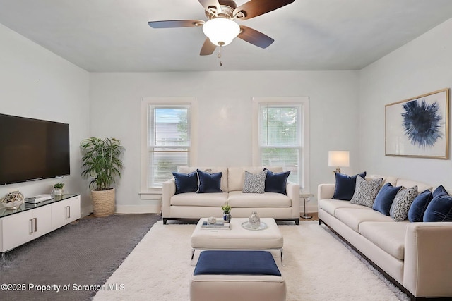 living area with carpet, healthy amount of natural light, a ceiling fan, and baseboards