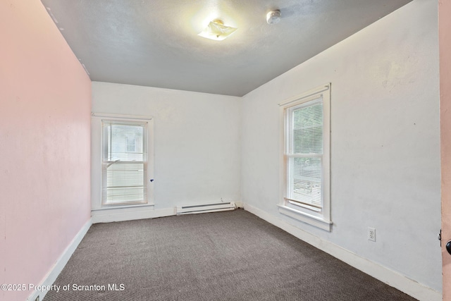 spare room featuring baseboard heating, dark carpet, and baseboards