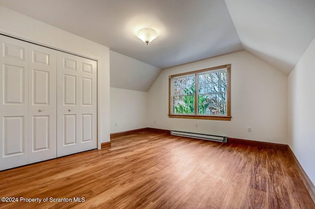 additional living space featuring light wood-type flooring, a baseboard radiator, and lofted ceiling