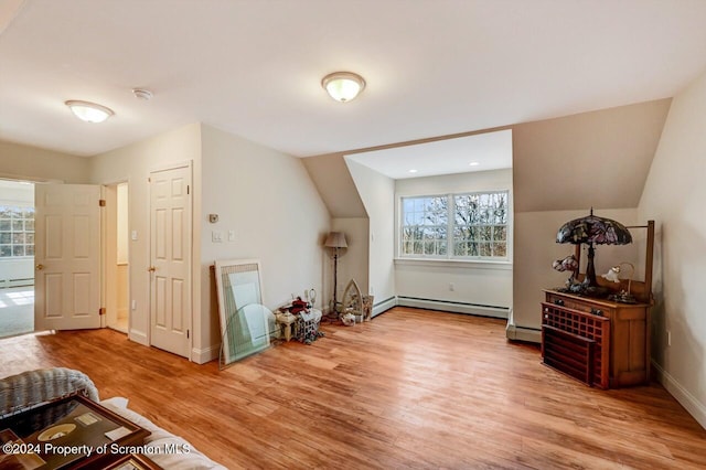 additional living space featuring baseboard heating and hardwood / wood-style floors