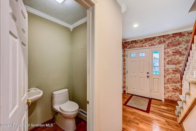 foyer featuring baseboard heating, ornamental molding, and light wood-type flooring