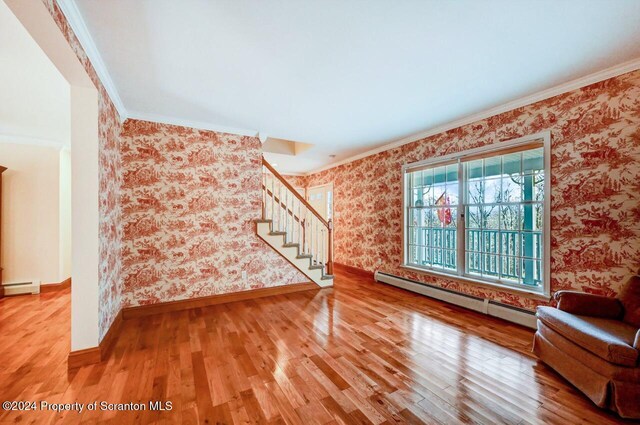 unfurnished living room featuring hardwood / wood-style flooring, ornamental molding, and a baseboard radiator