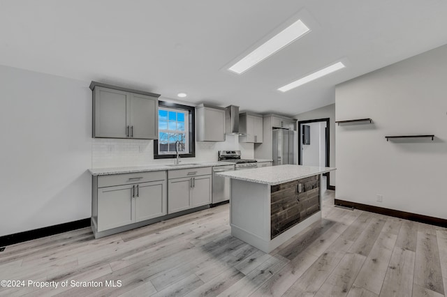 kitchen featuring gray cabinetry, sink, wall chimney exhaust hood, stainless steel appliances, and a kitchen island