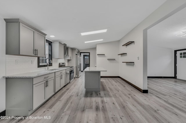 kitchen with light stone counters, gray cabinetry, stainless steel appliances, sink, and lofted ceiling