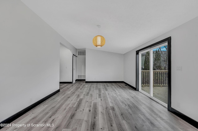 empty room featuring a barn door and light hardwood / wood-style flooring