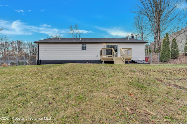 rear view of house with a lawn and a wooden deck