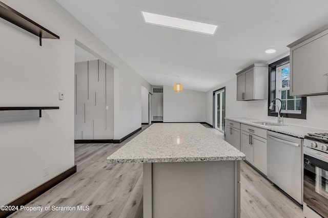 kitchen featuring stainless steel dishwasher, a kitchen island, gray cabinets, and sink