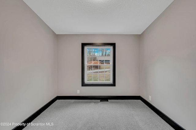 carpeted spare room featuring a textured ceiling