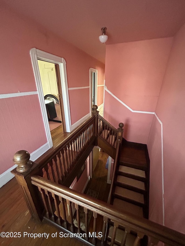 staircase featuring baseboards and wood finished floors