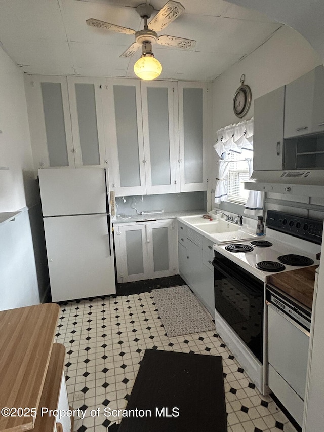 kitchen featuring range with electric cooktop, a sink, white cabinets, freestanding refrigerator, and light floors