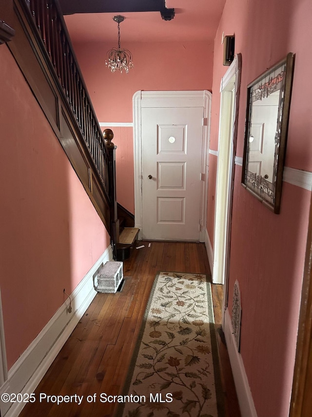 entryway featuring visible vents, baseboards, dark wood-style floors, stairs, and a chandelier