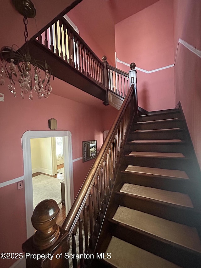 staircase with a high ceiling and an inviting chandelier