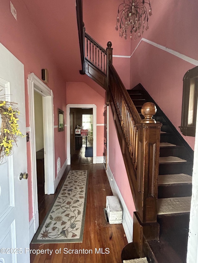 stairway featuring baseboards, a chandelier, and wood finished floors