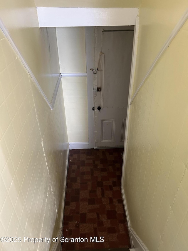 hallway with wainscoting and tile walls