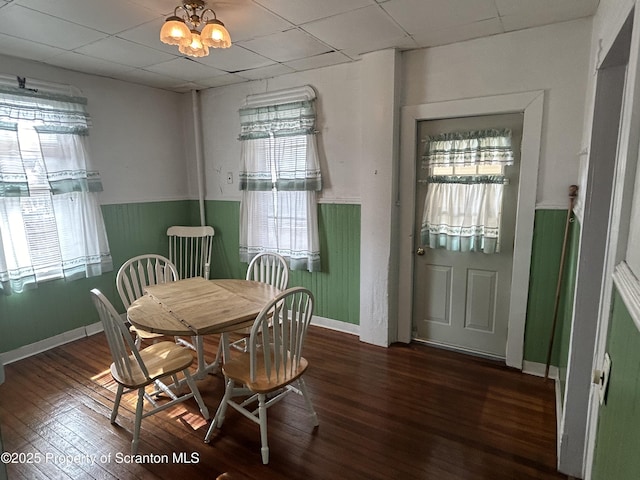 dining space featuring a paneled ceiling, wainscoting, dark wood finished floors, and a notable chandelier