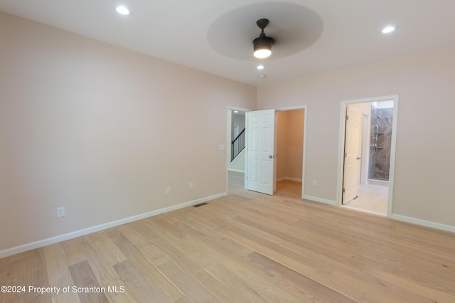 unfurnished bedroom featuring ceiling fan, light wood-type flooring, a spacious closet, connected bathroom, and a closet