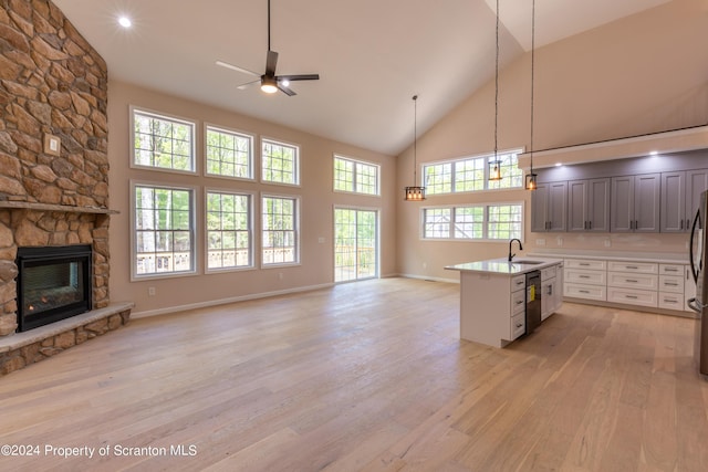 kitchen with sink, black dishwasher, pendant lighting, a fireplace, and white cabinets