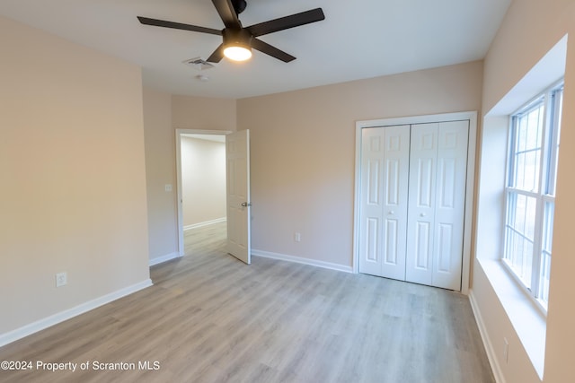 unfurnished bedroom with light wood-type flooring, a closet, and ceiling fan