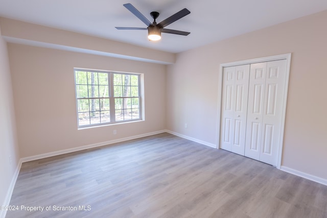 unfurnished bedroom featuring ceiling fan, light wood-type flooring, and a closet