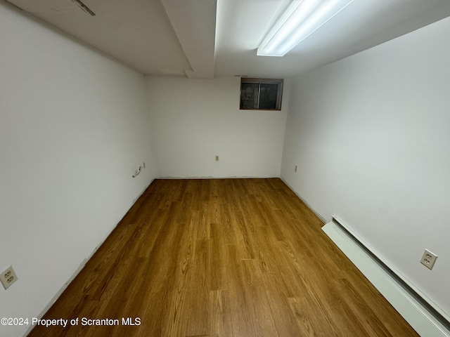 basement with baseboard heating and light hardwood / wood-style flooring