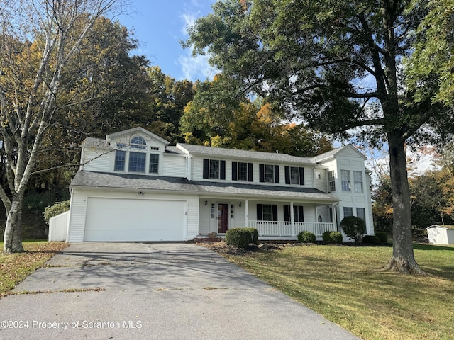 view of property with a front yard, a porch, and a garage