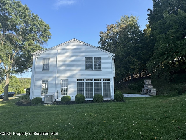 back of house with central air condition unit and a yard