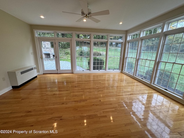 unfurnished sunroom with ceiling fan and radiator heating unit