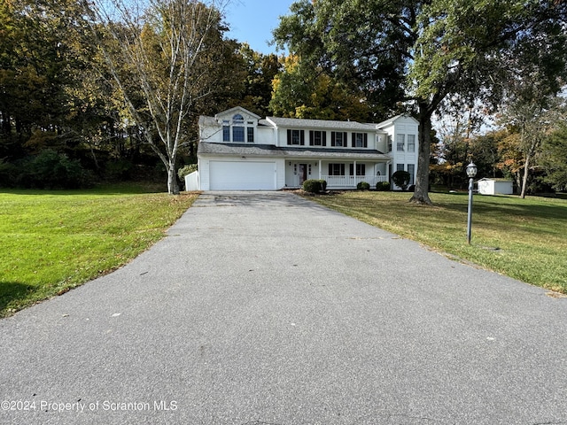 front facade featuring a garage, covered porch, and a front yard