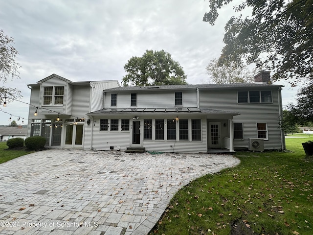 rear view of property with a lawn and ac unit