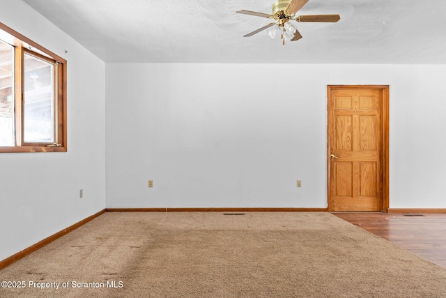 empty room featuring carpet floors, ceiling fan, a textured ceiling, and baseboards