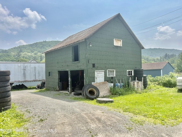 view of side of home featuring a mountain view, an outdoor structure, driveway, and a garage
