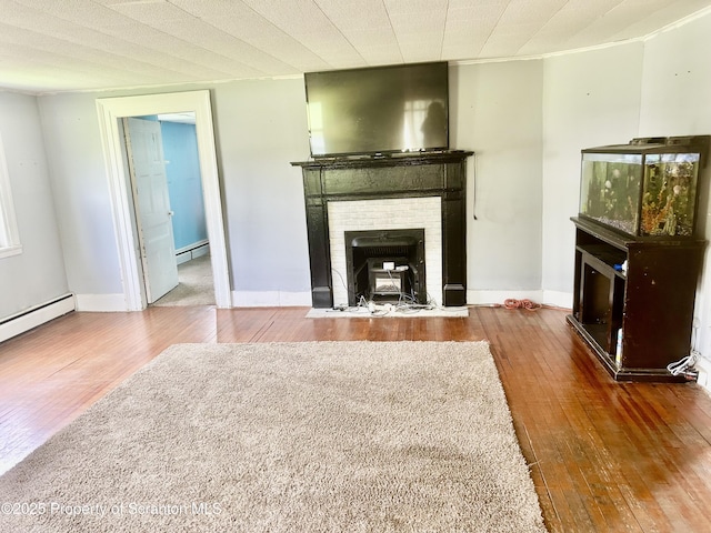 unfurnished living room featuring wood-type flooring, a fireplace, and a baseboard radiator