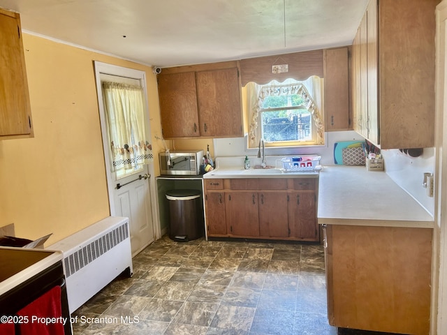kitchen featuring stainless steel microwave, light countertops, and brown cabinetry
