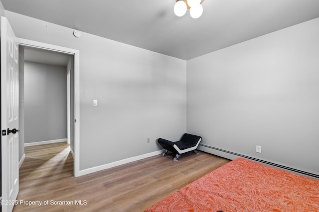 bedroom with hardwood / wood-style floors and a baseboard heating unit