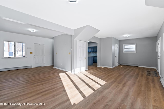 unfurnished living room with a baseboard radiator and wood-type flooring