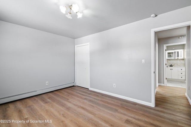 spare room with sink, a chandelier, light hardwood / wood-style flooring, and a baseboard radiator