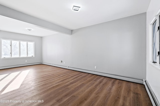 spare room featuring baseboard heating, hardwood / wood-style flooring, and beam ceiling