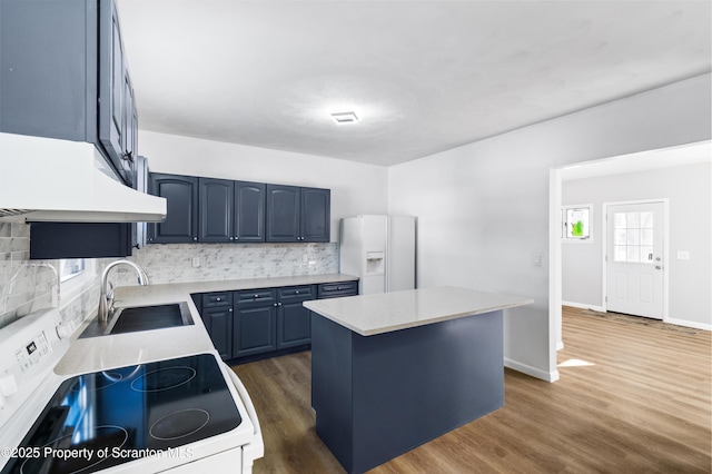 kitchen featuring sink, tasteful backsplash, blue cabinets, white appliances, and a kitchen island