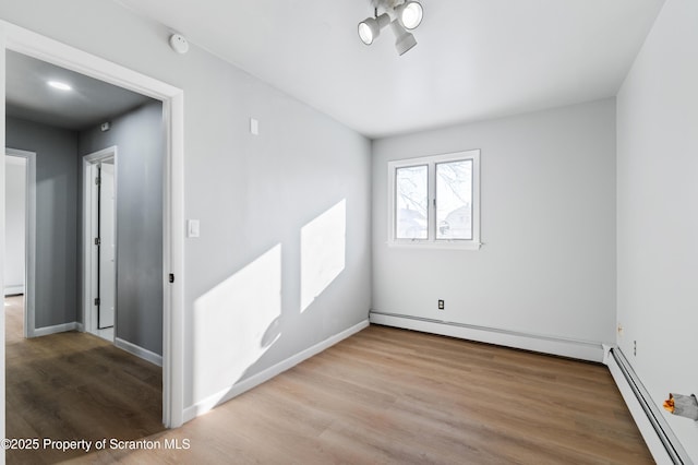 empty room with light wood-type flooring and a baseboard radiator